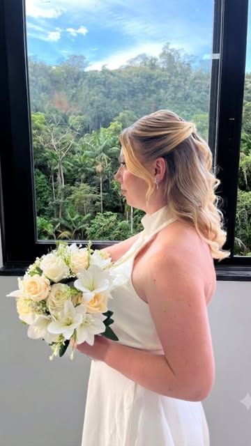 Noiva de perfil com buquê e maquiagem finalizada